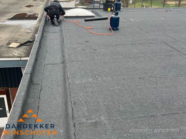 Dakdekker repareert bitumen dakbedekking op groot plat dak in Winschoten Dakdekker repareert bitumen dakbedekking op groot plat dak in Winschoten