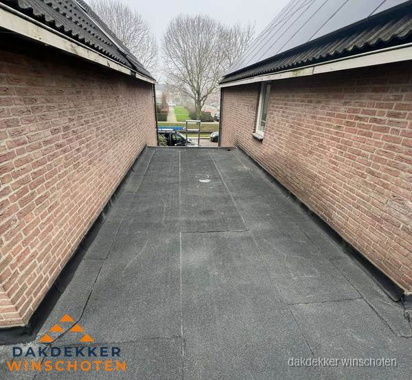 Plat dak met bitumen dakbedekking tussen bakstenen muren in Winschoten Plat dak met bitumen dakbedekking tussen bakstenen muren in Winschoten